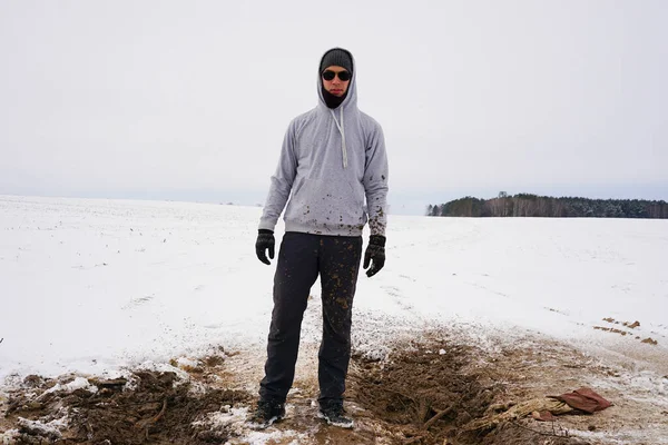 Elinde kürekle kirli elbiseli bir adam.