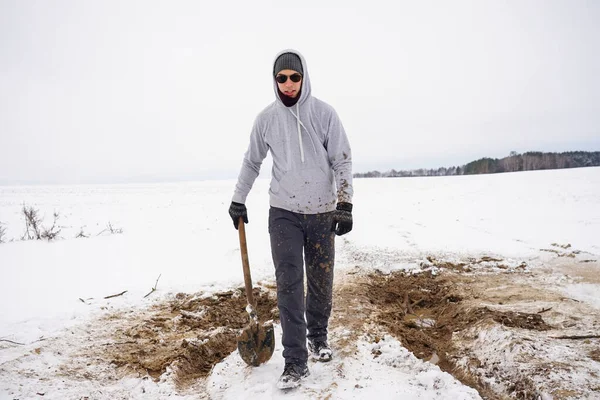 Karda çukur kazdıktan sonra çamura düşen adam. Pantolon ve giysiler kirlenmiş.