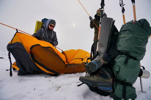 İki adam karda bir çadır kuruyor. Kış seferi sırasında aşırı koşullarda bir çadır kurmak. Kış yürüyüşü