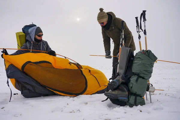 İki adam karda bir çadır kuruyor. Kış seferi sırasında aşırı koşullarda bir çadır kurmak. Kış yürüyüşü