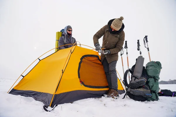 İki adam karda bir çadır kuruyor. Kış seferi sırasında aşırı koşullarda bir çadır kurmak. Kış yürüyüşü