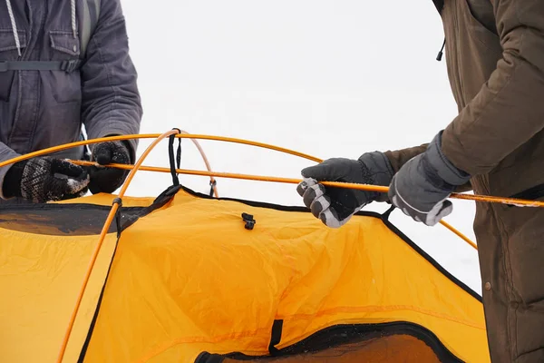 İki adam karda bir çadır kuruyor. Kış seferi sırasında aşırı koşullarda bir çadır kurmak. Kış yürüyüşü