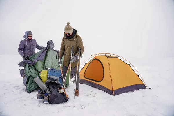 İki adam karda bir çadır kuruyor. Kış seferi sırasında aşırı koşullarda bir çadır kurmak. Kış yürüyüşü