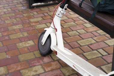 Parkta yakın planda elektrikli scooter var. Dışarısı soğuk ve karlı. İlkbaharda kar altında scooter.