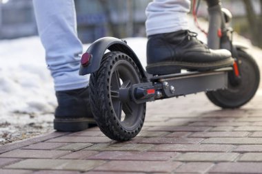 Elektrikli scooter yakın plan. Adam parkta elektrikli scooter 'ın yanında duruyor. İlkbahar parkında güzel bir scooter fotoğrafı.