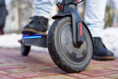 Elektrikli scooter yakın plan. Adam parkta elektrikli scooter 'ın yanında duruyor. İlkbahar parkında güzel bir scooter fotoğrafı.