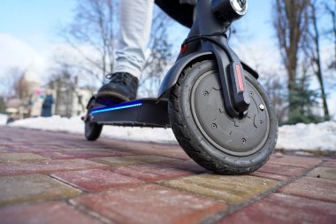 Elektrikli scooter yakın plan. Adam parkta elektrikli scooter 'ın yanında duruyor. İlkbahar parkında güzel bir scooter fotoğrafı.
