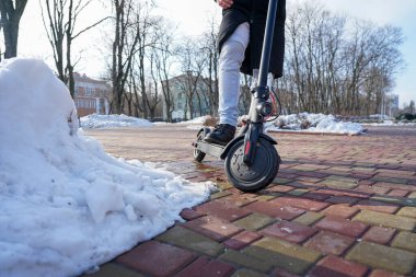 Elektrikli scooter yakın plan. Adam parkta elektrikli scooter 'ın yanında duruyor. İlkbahar parkında güzel bir scooter fotoğrafı.