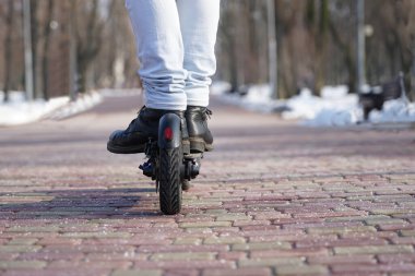 Adam parkta elektrikli scooter kullanıyor.