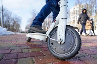 Adam parkta elektrikli scooter kullanıyor.