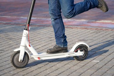 Elektrikli scooter yakın plan. Adam parkta elektrikli scooter 'ın yanında duruyor. Parktaki bir scooter 'ın güzel fotoğrafı.