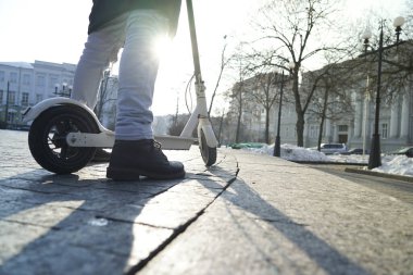 Elektrikli scooter yakın plan. Adam parkta elektrikli scooter 'ın yanında duruyor. Parktaki bir scooter 'ın güzel fotoğrafı.