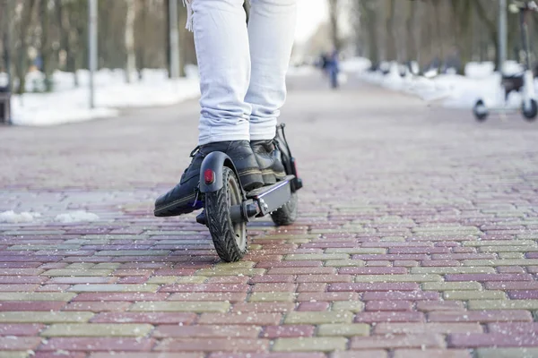 Leaktrik scooter 'ı yakın plan. Adam parkta elektrikli scooter 'ın yanında duruyor. Parktaki bir scooter 'ın güzel fotoğrafı.