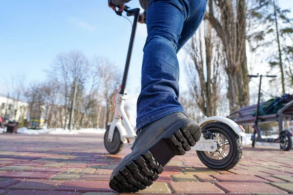 Adam baharda parkta elektrikli scooter 'a biniyor ve zıplıyor.