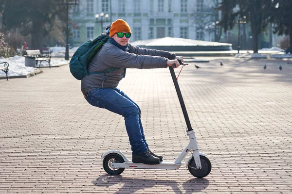 Guy Rides Electric Scooter Spring Park Wearing Warm Jacket Hat — Fotografia de Stock