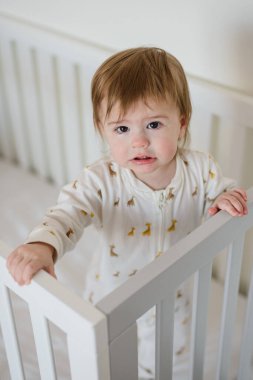 Uykucu, tatlı bir kız bebek. Sabahları yatakta duruyor.