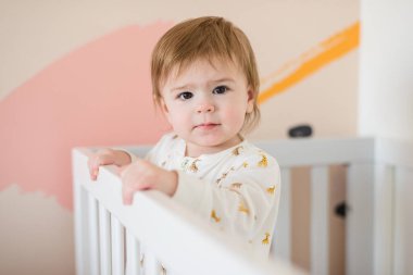 Uykucu, tatlı bir kız bebek sabahları yatakta dikiliyor.