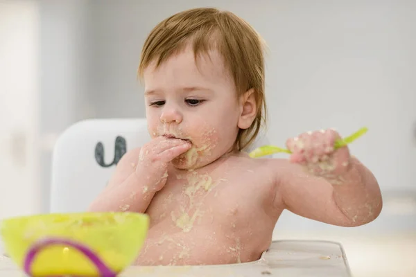 スプーンを使用するには 手で食べ物を食べるために笑顔面白い赤ちゃんの女の子研究 — ストック写真