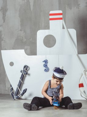 Denizci şapkalı kabin görevlisi gemi modeliyle oynuyor.