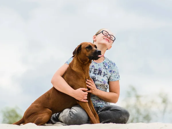 Gözlüklü kız köpeğini kucaklıyor ve öpüyor. — Stok fotoğraf