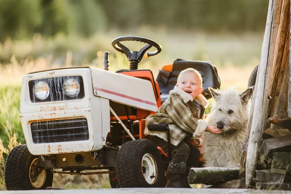 Loiro menino perto de cortador de grama cortador trator com cão amigo — Fotografia de Stock