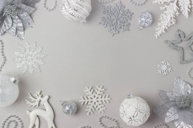 Tatil çerçevesi gri arka planda gümüş ve beyaz parlak noel süslemeleri yaptı. Mutlu Noeller, Noel ve Yeni Yıl konsepti. Üst görünüm, düz görünüm, boşluğu kopyala.