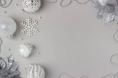 Tatil çerçevesi gri arka planda gümüş ve beyaz parlak noel süslemeleri yaptı. Mutlu Noeller, Noel ve Yeni Yıl konsepti. Üst görünüm, düz görünüm, boşluğu kopyala.