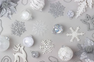Tatil desenleri gri arka planda gümüş ve beyaz parlak noel süslemeleri yaptı. Mutlu Noeller, Noel ve Yeni Yıl konsepti. Üst Manzara Düz Yat.