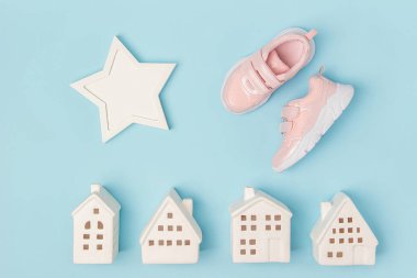 Pembe ayakkabılar ve mavi arka planda beyaz seramik evler. Yaratıcı spor konsepti. Üst Görünüm Düz.