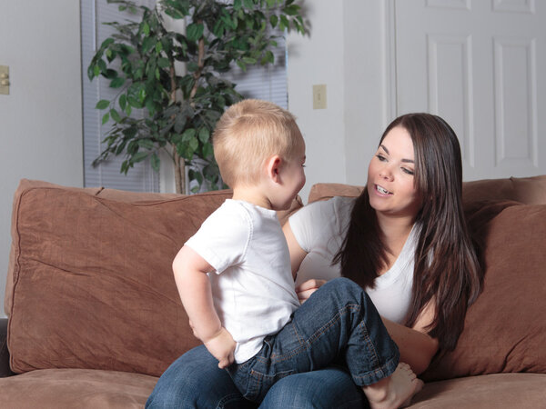 Young mother and toddler son enjoying playtime at home on the couch.