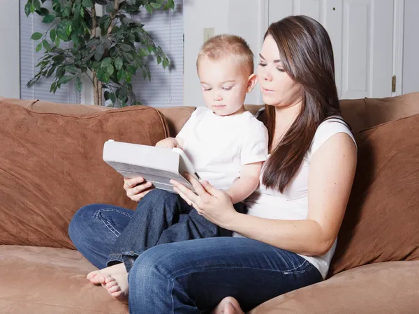 Jovem mãe mostrando criança para ler no tablet — Fotografia de Stock