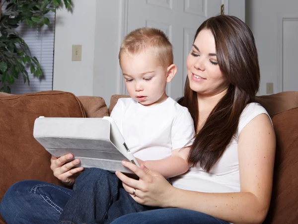 Giovane madre mostrando bambino a leggere su tablet Foto Stock