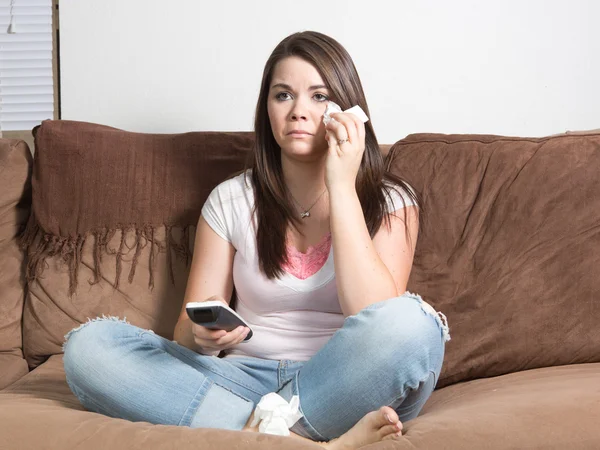 Lacrimosa donna caucasica seduta sul divano che tiene a distanza guardando la televisione tamponare gli occhi con tessuto . Foto Stock