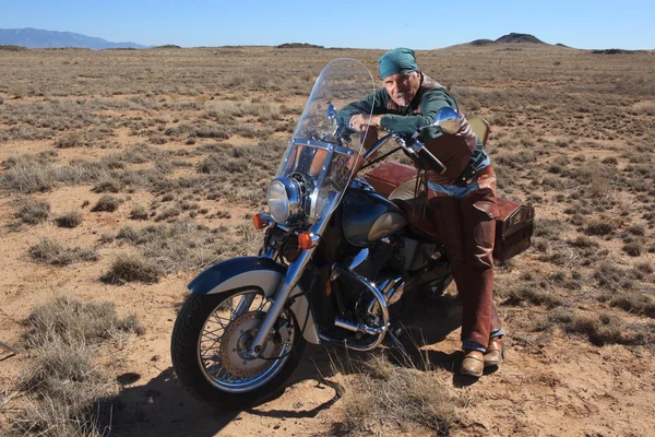 Chropowaty emeryturze człowiek z jego motocykli w południowo-zachodniej. — Zdjęcie stockowe