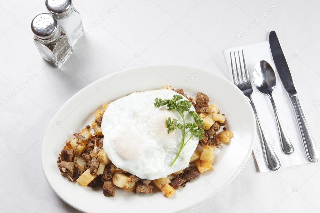 Corned beef hash breakfast plate with flatware and salt and pepper shaker