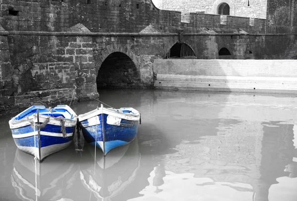 Puerto blanco y negro con dos barcos azules Imágenes De Stock Sin Royalties Gratis