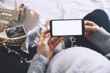Boş beyaz bir ekranla el ele tutuşan hamile bir kadın. Müstakbel annenin karnına ultrason fotoğrafları ve tıbbi test raporlarıyla yakın çekim. Hamilelik kavramı, jinekoloji.
