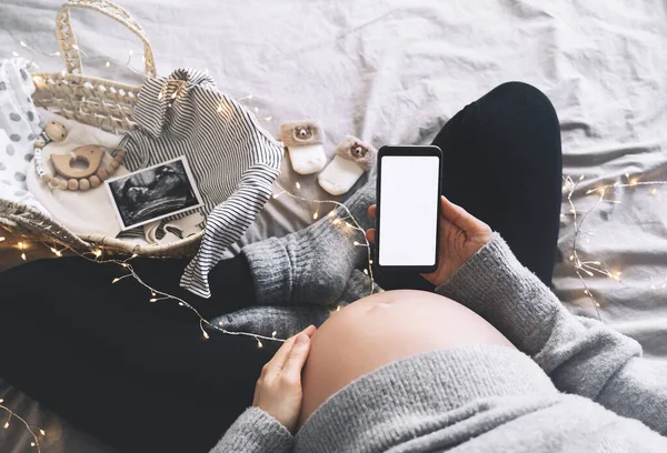 Kobieta Ciąży Trzyma Rękach Smartfon Pustym Białym Wyświetlaczem Zbliżenie Brzucha — Zdjęcie stockowe
