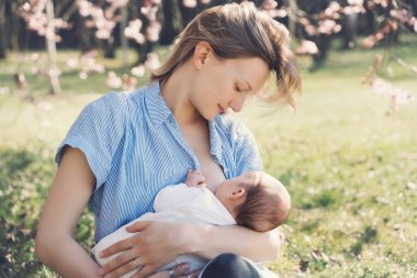 Güzel anne bebeğini emziriyor. Genç bir kadın yeni doğmuş bebeğini emziriyor. Emzirme, doğum sonrası dönemi, doğal annelik kavramı. Anne ve bebek doğada..