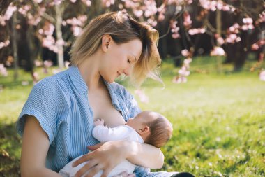 Güzel anne bebeğini emziriyor. Genç bir kadın yeni doğmuş bebeğini emziriyor. Emzirme, doğum sonrası dönemi, doğal annelik kavramı. Anne ve bebek doğada..