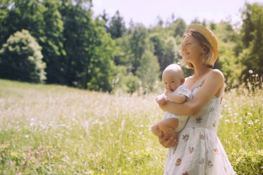 Anne ve bebek. Doğal annelik ve annelik kavramı. Güzel kadın ve küçük bebek yeşil doğada birlikte mutlular. Dışarıda çocuklu bir anne..