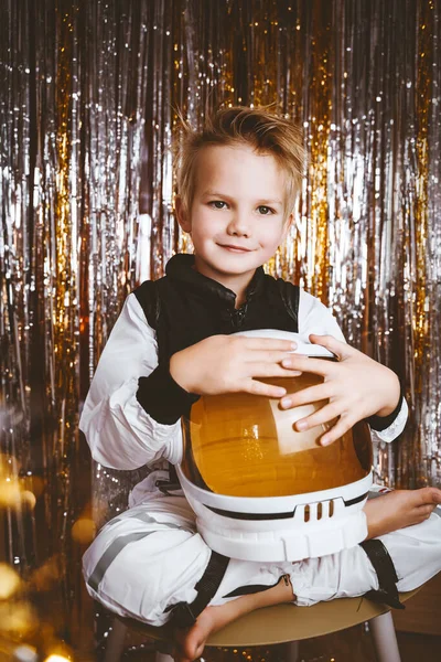 Child in fancy dress of astronaut pilot costume having fun at masquerade party in festive background with foil curtain decorations. Kids birthday party, Halloween, New Year, Celebration any Holiday.