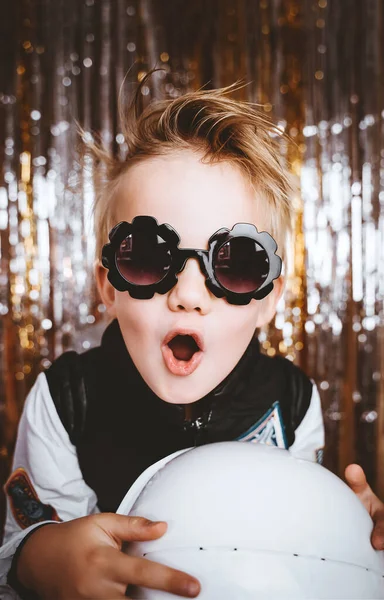 Komik çocuk portresi, süslü astronot elbisesi içinde folyo perde süslemeleriyle şenlik arka planında eğleniyor. Çocukların doğum günü partisi, Cadılar Bayramı, Yeni Yıl, herhangi bir bayramı kutlamak..