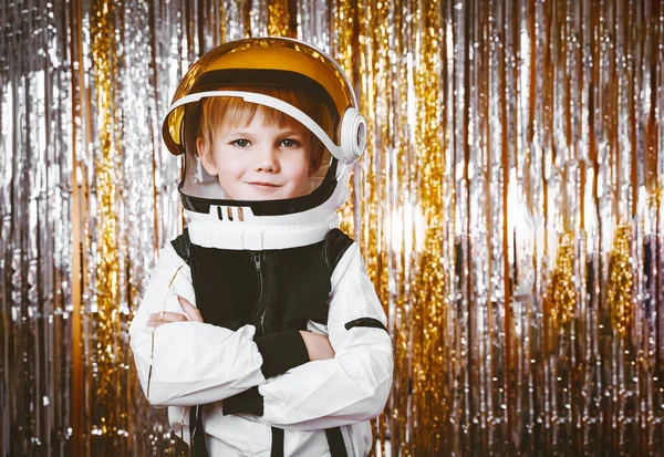 Child in fancy dress of astronaut pilot costume having fun at masquerade party in festive background with foil curtain decorations. Kids birthday party, Halloween, New Year, Celebration any Holiday.