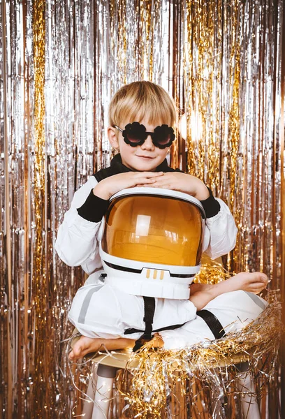 Child in fancy dress of astronaut pilot costume having fun at masquerade party in festive background with foil curtain decorations. Kids birthday party, Halloween, New Year, Celebration any Holiday.