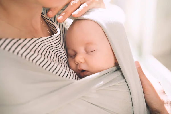 Bebek giyiyorum. Anne ve bebek doğada. Paket taşıyıcıdaki bebek. Yeşil nane renginde bebek askısı taşıyan bir kadın. Yeşil ebeveynlik kavramı, doğal annelik, doğum sonrası dönem..