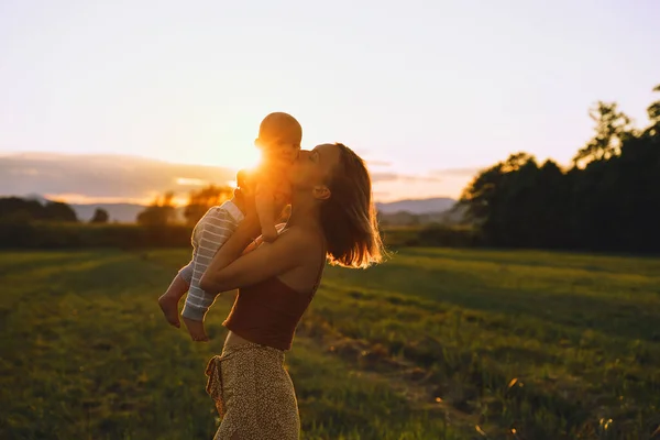 日没時に母親と赤ん坊を愛する 自然の中で美しい女性と小さな子供の背景 自然の母親の概念 夏の屋外で幸せな健康的な家族 肯定的な人間の感情や感情 — ストック写真