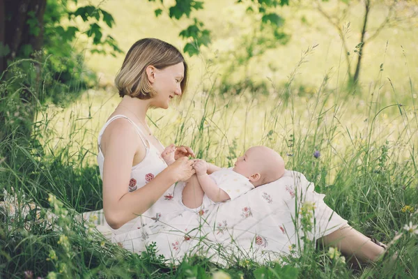 Beautiful mother and baby on nature. Young woman with her baby in harmony. Concept of natural motherhood, human happiness, healthy family, eco sustainable lifestyle. Loving mom with child outdoors.