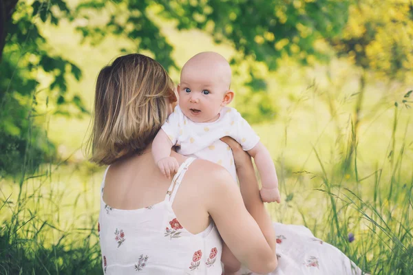 Beautiful mother and baby on nature. Young woman with her baby in harmony. Concept of natural motherhood, human happiness, healthy family, eco sustainable lifestyle. Loving mom with child outdoors.