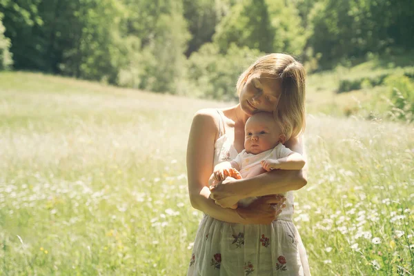 Anne ve bebek. Doğal annelik ve annelik kavramı. Güzel kadın ve küçük bebek yeşil doğada birlikte mutlular. Dışarıda çocuklu bir anne..